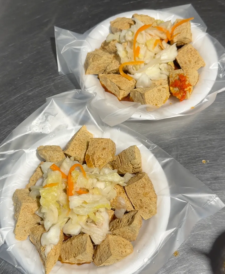 兩份發財車臭豆腐盛在紙盤裡，炸得金黃的臭豆腐鋪上台式泡菜與辣醬