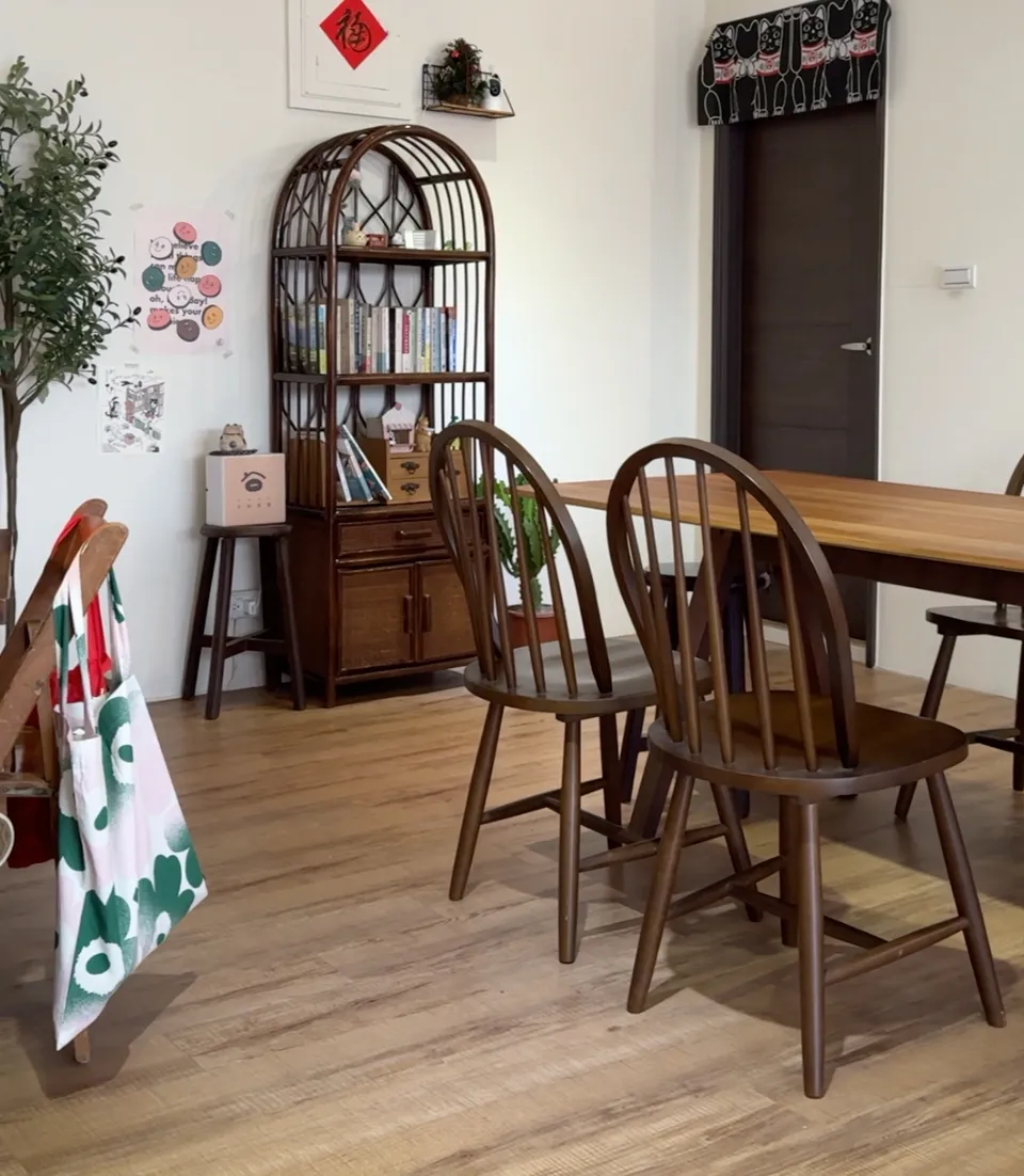 日知常屋咖啡廳的內用座位區,木質長桌搭配溫莎椅,牆邊藤編書架擺滿書本,空間簡約明亮
