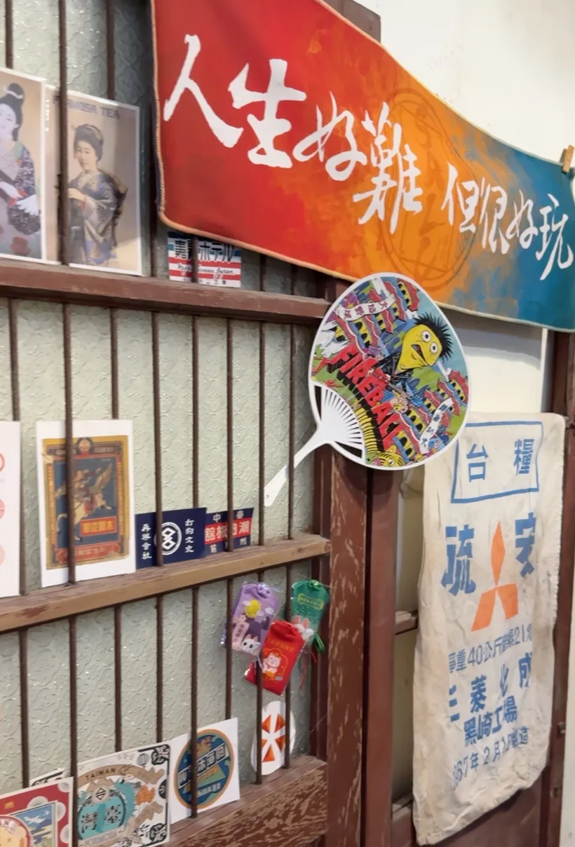 三合號牆面的懷舊老物件收藏,日文彩色布條、浮世繪明信片、台糧麻布袋與老鐵窗構成好拍的一角